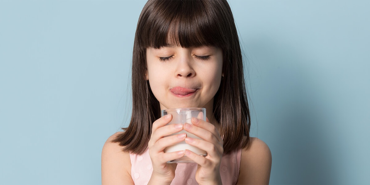 happy smiling girl enjoying glass of milk